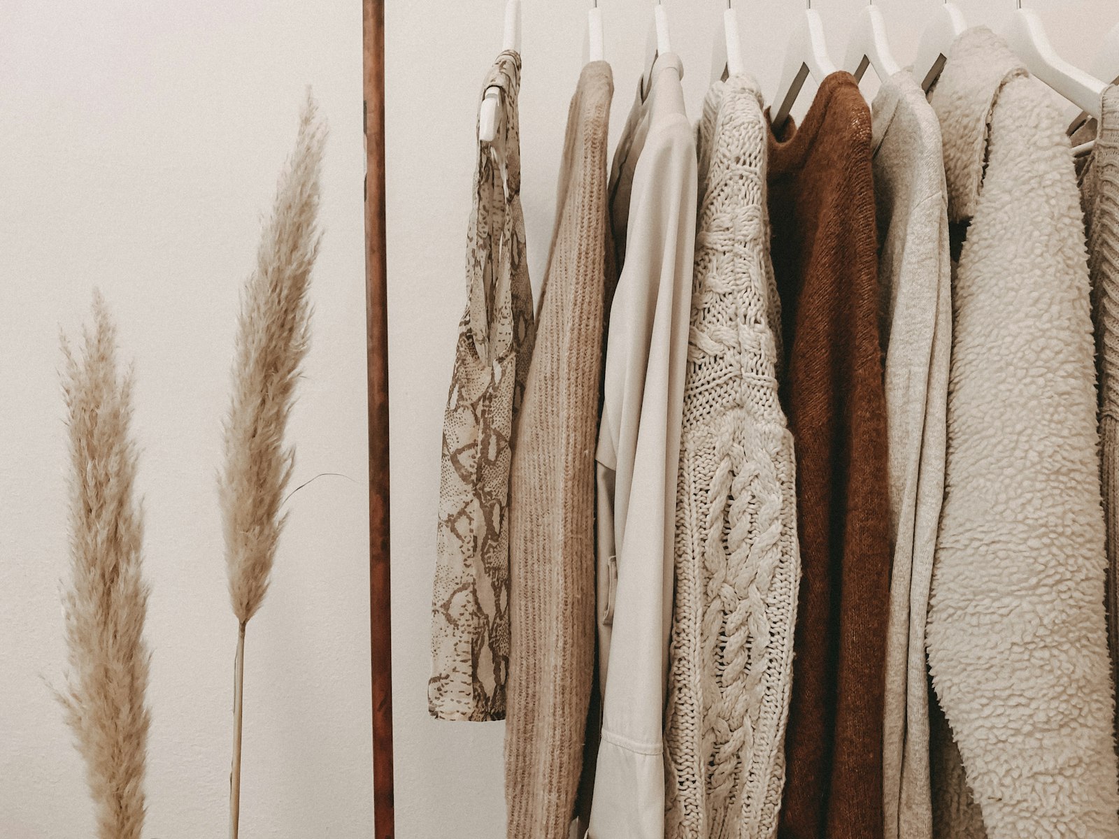 Neutral knits and layers hanging on a wooden rack